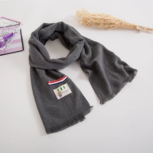 Detail of dark grey kids cashmere scarf featuring a cute bear patch and fringe edges