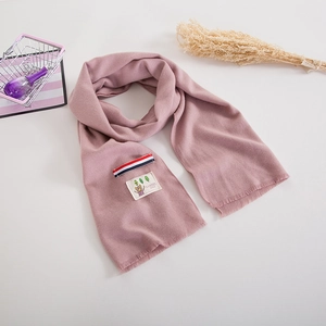 Detail of pink knitted kids scarf featuring a cute bear patch and tricolor ribbon accent