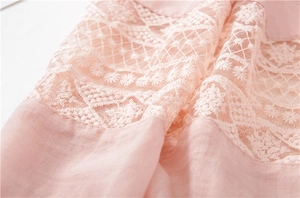 Macro shot of light pink lace fabric with detailed embroidery and floral hollow patterns