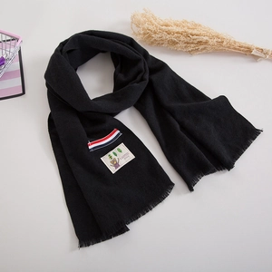 Detail of soft black kids scarf featuring colorful stripes, bear patch and fringed edges