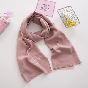 Detail eines rosa gestrickten Kinderschals mit Libellen-Stickerei und Fransen am Rand