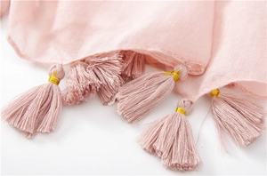 Close-up of soft pink scarf fringe with elegant gold thread wrap and fabric texture