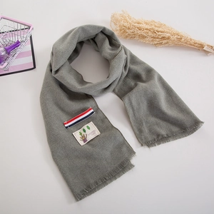 Soft gray knit children's scarf with striped label, bear patch, and fringe details