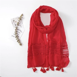 Detail of red summer shawl with delicate lace patchwork and handmade tassel fringe decor