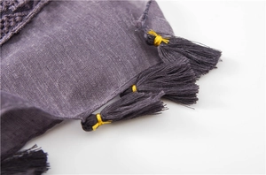 Detailed macro view of purple fabric scarf with gold-wrapped fringe tassels and texture