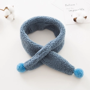 Soft blue plush crossover scarf for kids featuring fluffy pom-poms on clean white background