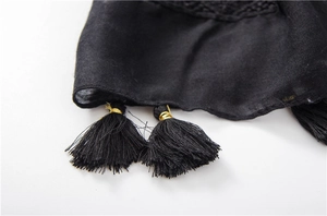 Detail of black scarf featuring elegant tassels with gold metal rings and fine embroidery
