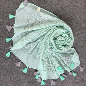 Dettaglio di sciarpa verde menta con quadrati argentati e lunghe frange decorative