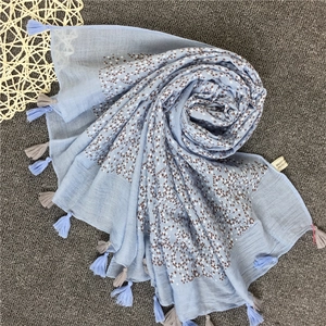 Dettaglio di sciarpa in cotone azzurro con motivi geometrici e piccole frange