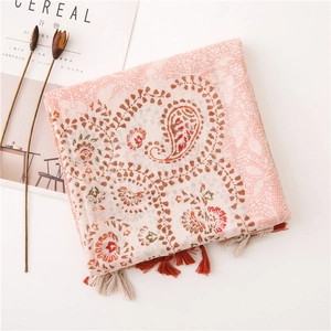 Detail of pink paisley scarf with tassels next to a magazine for a bohemian style