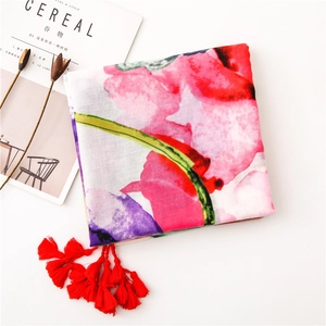 Flat lay of a floral print scarf with red tassels next to a minimalist lifestyle magazine