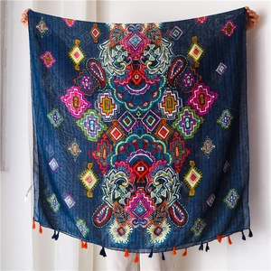 Détail d'une écharpe bohème aux motifs géométriques vifs et pompons colorés