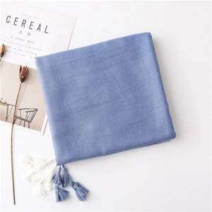 Detail of blue cotton scarf texture with delicate fringe tassels on a minimalist background