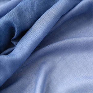 Close-up of blue cotton fabric showing detailed twill texture and soft gradient colors