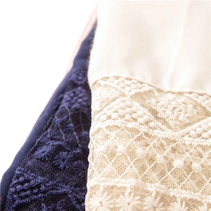 Lace detail of a solid color scarf featuring intricate floral embroidery and navy accents