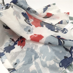 Detail of floral printed scarf with light blue tassels and soft acrylic fabric texture