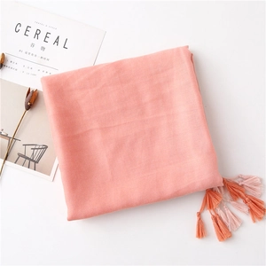 Detail of soft coral cotton scarf featuring delicate knit texture and elegant fringed edges