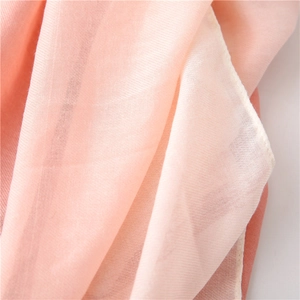 Close-up of soft peach cotton scarf showing delicate woven texture and hemmed edges