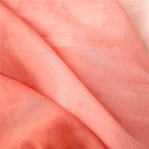 Close-up of coral pink cotton fabric texture with natural fibers and soft wrinkles