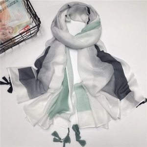Detail of gradient stripe cotton shawl with tassels in white, grey, and mint green