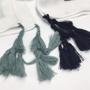 Close-up of dual-color tassels in grey-green and navy blue on a white cotton scarf