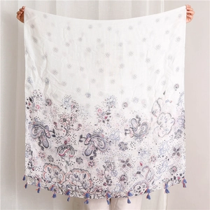 Détail de l'écharpe en coton et lin avec imprimés paisley et franges à pompons bleus