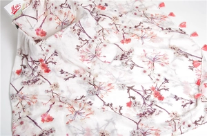 Close-up of white linen-cotton scarf showing delicate purple floral prints and pink tassels