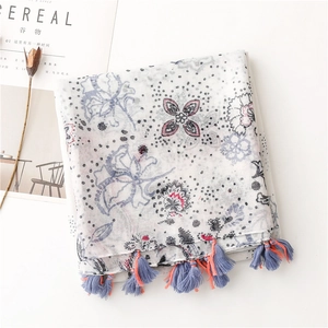 Vue détaillée d'une écharpe en lin à fleurs avec franges bohèmes et pompons doux