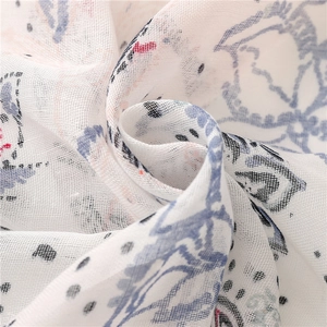 Gros plan du tissu de l'écharpe en coton blanc avec des motifs floraux géométriques