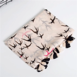 Pastel cotton scarf with swallow print and tassels shown folded on a white surface