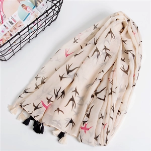 Lightweight beige swallow print scarf with tassels on clean white background