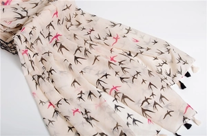 Close-up of lightweight swallow print scarf with elegant black and white tassels
