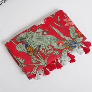 Detail of red floral scarf with bird prints and delicate fringe tassels on white backdrop