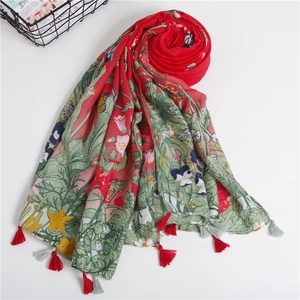 Detail of red floral cotton scarf featuring bird patterns and fringe tassel edges