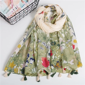 Detail of floral printed cotton scarf featuring tassels and a soft nature-inspired pattern