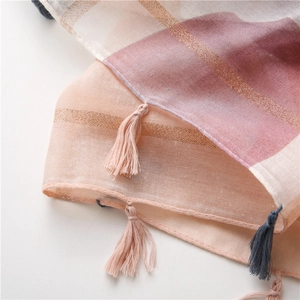 Détail d'écharpe en coton et lin rose avec rayures dorées et finitions à franges