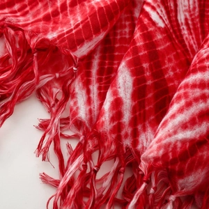 Λεπτομερής όψη κόκκινου και λευκού κασκόλ tie-dye με χειροποίητα κρόσσια και βαμβακερή υφή