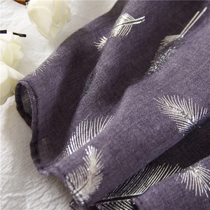 Close-up of silver feather print on lightweight dark purple cotton linen scarf fabric