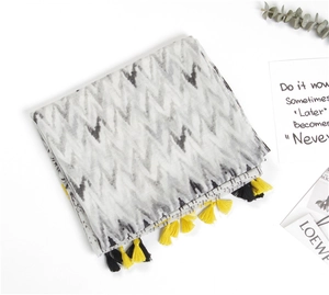 Detail of grey wave pattern linen scarf featuring yellow and black fringe tassels
