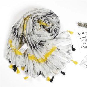 Detail of thin striped scarf with black and yellow tassels on a minimalist background
