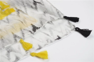 Detail of cotton linen scarf featuring gray abstract ink prints and yellow tassels