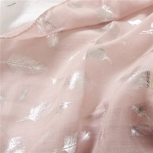 Close-up of pink linen scarf featuring elegant silver foil feather patterns and texture