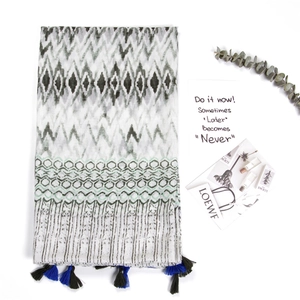 Detailed view of geometric print linen scarf with dark navy blue handmade tassels