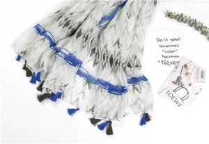 Flat lay of cotton linen scarf with ethnic patterns, blue stripes, and fringe tassels
