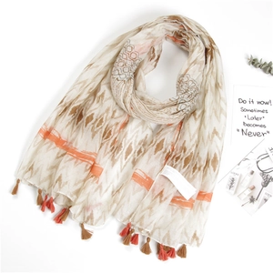 Detail of cotton linen scarf with ethnic patterns and orange tassels on a white background