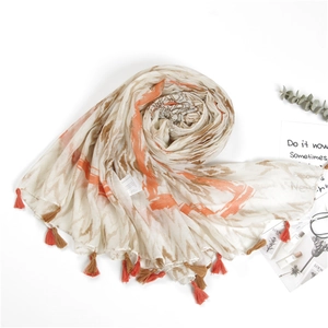 Detail of cotton linen scarf featuring orange tie-dye prints and handmade tassels