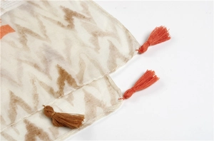 Detail of printed cotton linen scarf featuring handmade orange tassels and geometric pattern