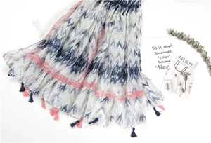Detail showing the cotton linen scarf's blue wave tie-dye patterns and colorful tassels
