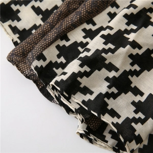 Detailed view of houndstooth scarf showing soft fabric texture and fine edge stitching