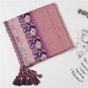 Detail of pink bohemian scarf featuring ethnic patterns and colorful fringe tassels